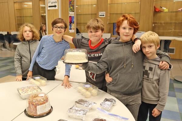 Middle school students proudly displaying a cake they won during the musical cakes activity.