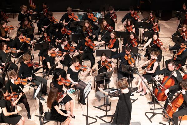 A photo of music teacher Andrea von Oeyen leading the Oyster River High School orchestra.