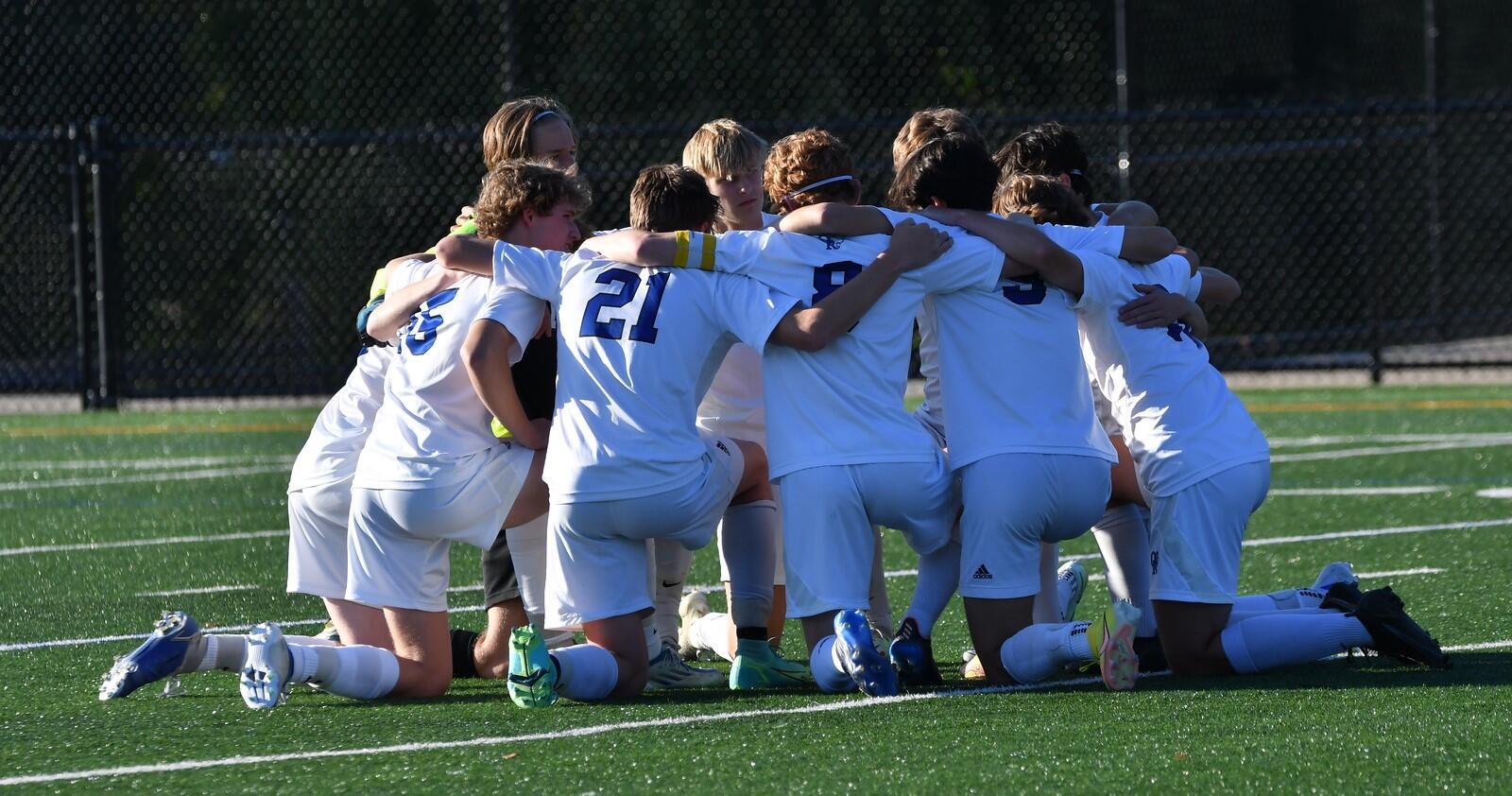 Boys soccer players in huddle on the field